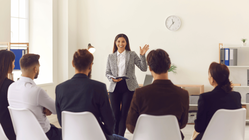 smiling company manager or team leader greeting workers or interns in corporate meeting